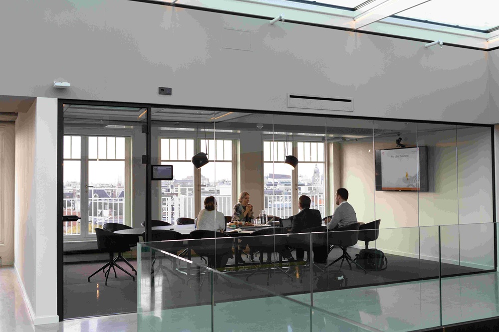 A picture of a private office with 4 people around a boardroom table